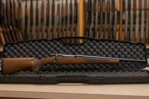 A prospective buyer and shop professional reviewing an unloaded Davis firearm at a workbench, with a lockbox and paperwork nearby